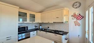 a kitchen with white cabinets and a clock on the wall at Casa del Comandante- Bluchalet in Cervo