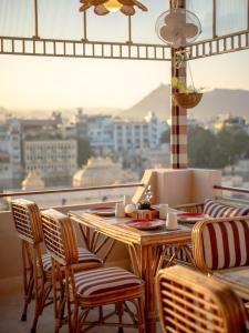 une table et des chaises sur un balcon avec vue sur une ville dans l'établissement Bun and Bunks, à Udaipur 10 autres photos