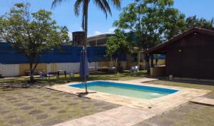 une piscine avec un parasol dans un jardin dans l'établissement Pousada Perolas de Itanhaem, à Itanhaém