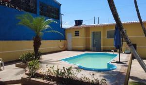 une piscine devant un immeuble avec un palmier dans l'établissement Pousada Perolas de Itanhaem, à Itanhaém