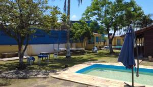 une piscine avec un parasol en face d'un bâtiment dans l'établissement Pousada Perolas de Itanhaem, à Itanhaém 5 autres photos