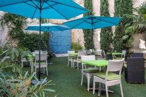 オランジュにあるHôtel L'Herbier d'Orangeのパティオ(テーブル、椅子、青いパラソル付)