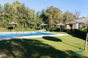 een zwembad in een tuin met parasols bij Zuri's Loft Islantilla Golf in Isla Cristina