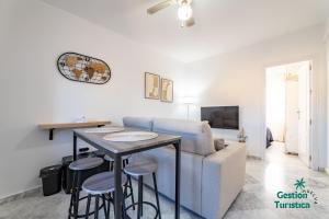 een woonkamer met een bank en een tafel met krukken bij Zuri's Loft Islantilla Golf in Isla Cristina