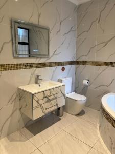 een badkamer met een wastafel, een toilet en een spiegel bij Pink Rock Villa in Durban