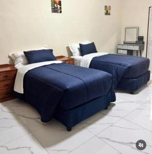twee bedden met blauwe dekens in een kamer bij Pink Rock Villa in Durban