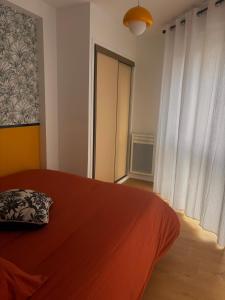 een slaapkamer met een bed met een rode deken en een raam bij Charmant appartement in Vitré