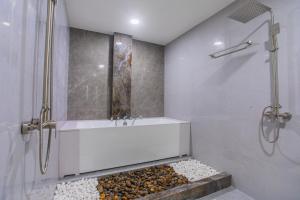 a bathroom with a tub and a shower and rocks at Lonuhiri at Dhigurah in Dhigurah +33 photos