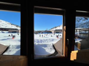 a view from a window of a group of people playing in the snow at Dinastia Case Snow Apartment in Passo del Tonale