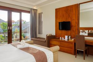 een hotelkamer met een bed, een bureau en een televisie bij Lebak Bali Residence in Canggu