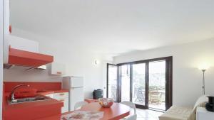 een keuken met rode kasten en een tafel in een kamer bij Il Porto 13 - Goelba in Porto Azzurro