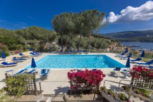 een zwembad van het resort met stoelen en bloemen bij Il Porto 13 - Goelba in Porto Azzurro