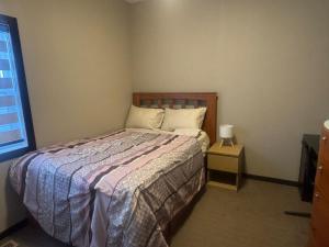 a bedroom with a bed and a nightstand and a window at Panorama Haven in Calgary