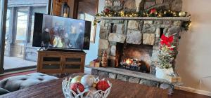 a living room with a stone fireplace with a television at Lakefront Hot Tub Canoes Game Room Wood FP in Gouldsboro