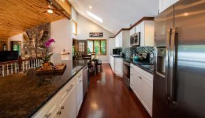 a large kitchen with white cabinets and black appliances at Lakefront Hot Tub Canoes Game Room Wood FP in Gouldsboro