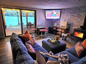 a living room with a blue couch and a tv at Lakefront Hot Tub Canoes Game Room Wood FP in Gouldsboro +94 photos