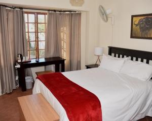 um quarto com uma cama, uma escrivaninha e uma janela em Siesta B&B em Vryheid