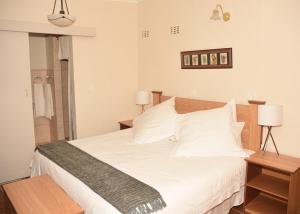 um quarto com uma cama com lençóis e travesseiros brancos em Siesta B&B em Vryheid