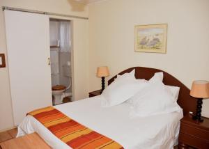 um quarto com uma cama com lençóis e travesseiros brancos em Siesta B&B em Vryheid