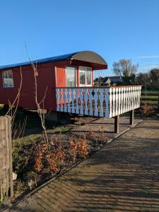 un wagon de train immobilisé sur les rails à côté d'une clôture dans l'établissement Shepherd's hut "Het Schoehuijs", à Sint Maartensbrug
