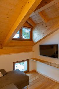 un soggiorno con soffitti in legno e TV a schermo piatto di Appartamenti Dolomites Elements a Caprile