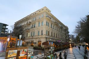 バクーにあるAzcot Hotel - Nizami Streetの前を歩く人々の並ぶ大きな建物
