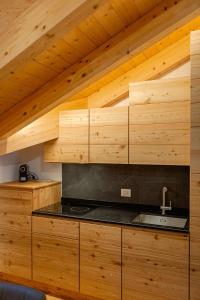 una cucina con mobili in legno e un lavello di Appartamenti Dolomites Elements a Caprile Altre 90 foto