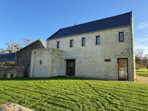 an old stone house with a black roof at Le Pressoir, maison au calme, jardin, terrasse, 3 chambres, 2 sdb, 2 WC, proche Bayeux et Arromanches au coeur des plages du débarquement in Longues-sur-Mer