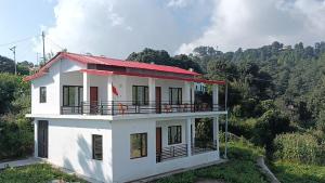 a white house with a red roof on a hill at Apple Hilltop Homestay in Chaubattia