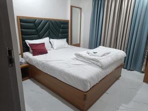 Un dormitorio con una cama con sábanas blancas y almohadas rojas. en The Lions Hotel, en Badlapur