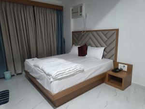 Un dormitorio con una cama grande con sábanas blancas. en The Lions Hotel, en Badlapur