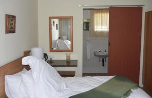 een slaapkamer met een bed en een badkamer met een wastafel bij Siesta B&B in Vryheid