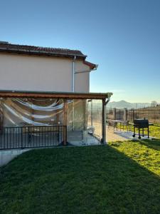 eine überdachte Terrasse mit einem Tisch und einem Grill in der Unterkunft Къща за гости Пегас in Welingrad