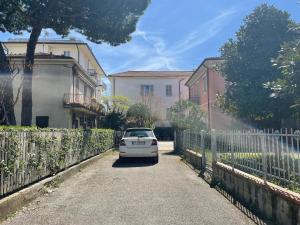 a white car parked on a road next to a fence at Grande villa al mare - Casa Goldoni in Rimini