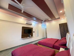 une chambre avec deux lits et une télévision au mur dans l'établissement Rivana Retreat, à Dehradun 14 autres photos
