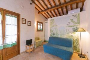 a living room with a blue chair and a television at Casetta di Pietra by ElbaSummer in Marciana