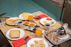 a table topped with plates of breakfast food and orange juice at Riad La Porte Rouge By La Siredrah in Marrakesh