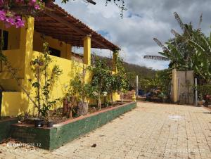 a yellow building with potted plants next to a sidewalk at Chalé nas nuvens in Meruoca