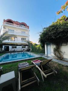 ルクソールにあるSet ma'atの芝生の椅子2脚付きのスイミングプール、建物