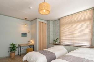 a bedroom with two beds and a window with blinds at 栞-shiori-FUNAKURA in Ishigaki Island