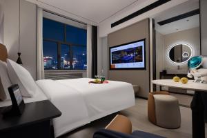 ein Hotelzimmer mit einem großen weißen Bett und einem Tisch in der Unterkunft Huanzhi Hotel Hulunbuir Hailar Railway Station Branch in Hulunber