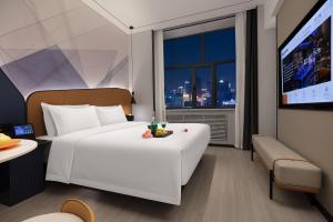 ein Hotelzimmer mit einem großen weißen Bett und einem Fenster in der Unterkunft Huanzhi Hotel Hulunbuir Hailar Railway Station Branch in Hulunber