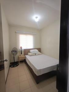 Un dormitorio con una cama con ventilador y una ventana. en Teves Suite Lipa City, en Lipá