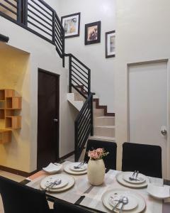 Un comedor con una mesa con sillas y un jarrón. en Teves Suite Lipa City, en Lipá