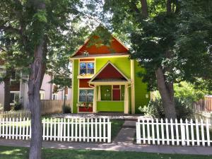 una piccola casa gialla e verde con una recinzione bianca di Remington Flats a Fort Collins
