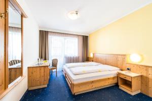 a bedroom with a large bed and a desk at Pension Astoria in Naturno
