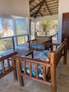 een kamer met houten banken, een tafel en ramen bij Casa do Capitao in Guajiru