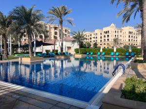 ein großer Swimmingpool mit Palmen und Gebäuden in der Unterkunft Luxury Stay on Saadiyat Island - Pool, Gym, Parking in Abu Dhabi