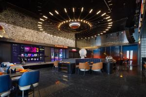 ein Restaurant mit Tischen und Stühlen und einem Kronleuchter in der Unterkunft Huanzhi Hotel Hulunbuir Hailar Railway Station Branch in Hulunber