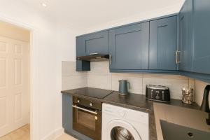 een keuken met blauwe kasten en een wasmachine bij Modern Tiny Home - Ideal for Work Stays & Parking in Pocklington +10 foto's